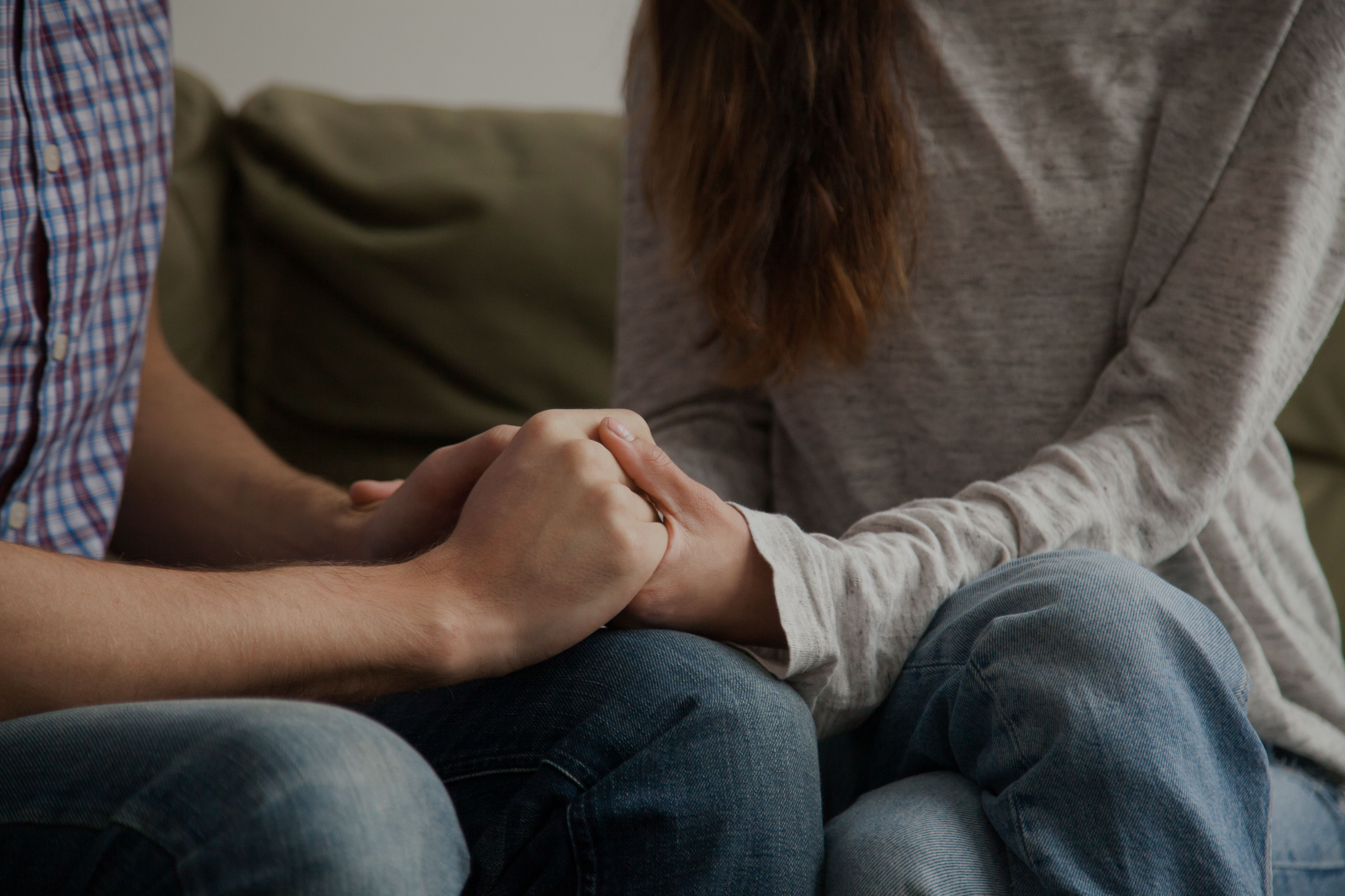 A couple sits holding hands tightly while undergoing an XO Marriage Intensive